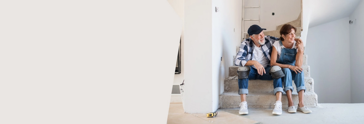 Frau und Mann sitzen auf einer Treppe im Rohbau
